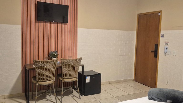 Quarto | Suíte com Ar | Mesa para refeições e frigobar.